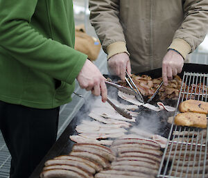 Two expeditioners barbeque bacon and other meats al fresco.