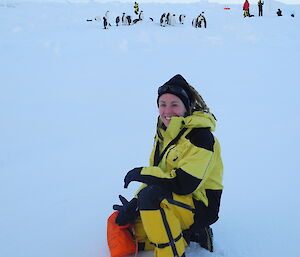 Dr Jessica Melbourne-Thomas on the sea ice with emperor penguins behind