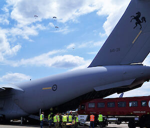 Red bus being loaded onto the back of a plane