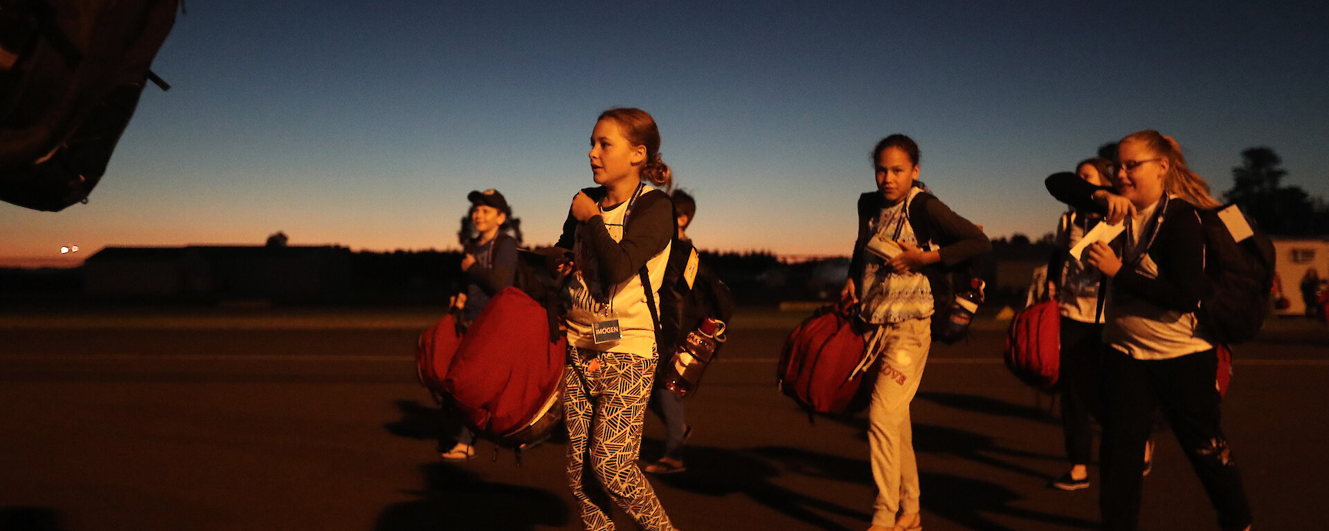 Students walking toward plane in semi-darkness.