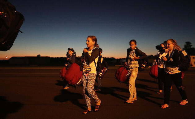 Students walking toward plane in semi-darkness.