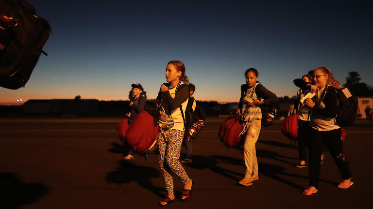 Students walking toward plane in semi-darkness.