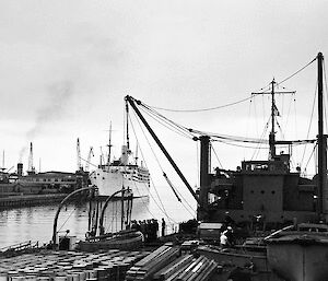 Photo of a ship along side a wharf with another ship in the background.