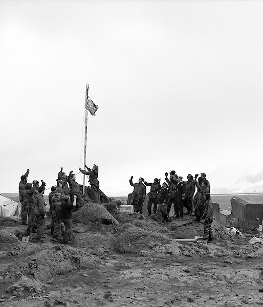 A man raises the flag in a black and white photo.