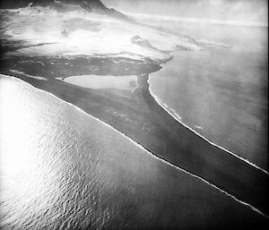Black and white photo taken from the air of an island with a long spit.