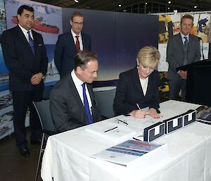 Ministers sitting at the table signing a document.