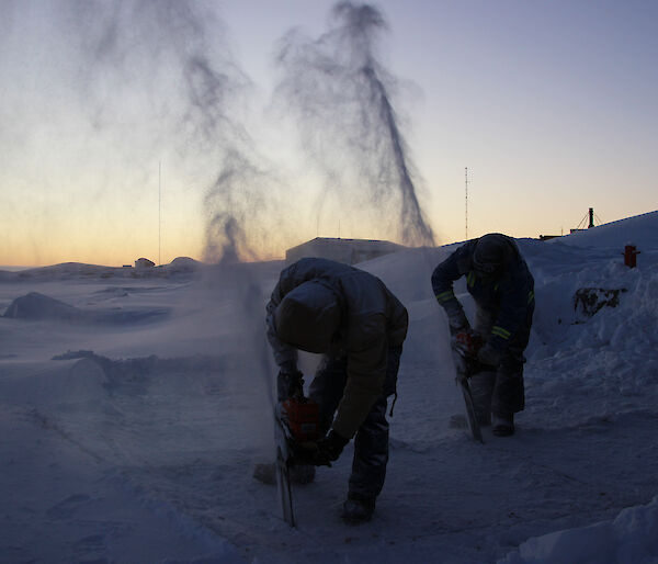 Expeditioners use a chainsaw to cut into the sea ice at Mawson station in preparation for their midwinter swim