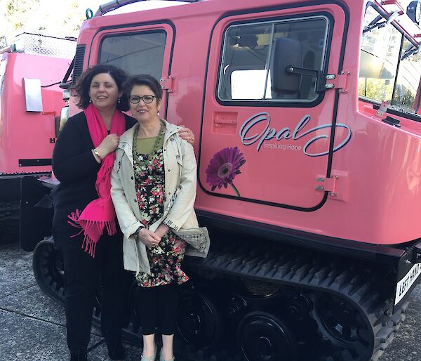 Social club president Mel Pike and BreastScreen Tasmania representative Lyn Gibson standing in front of the pink Hägglunds outside of the Antarctic Division in Kingston Tasmania