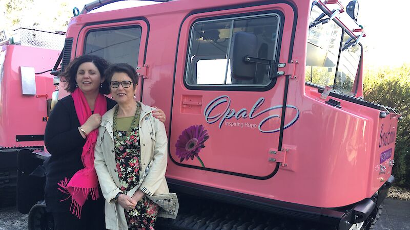 Social club president Mel Pike and BreastScreen Tasmania representative Lyn Gibson standing in front of the pink Hägglunds outside of the Antarctic Division in Kingston Tasmania