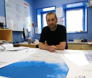 Operations specialist, Anthony Hull, in his office with a map of Antarctica