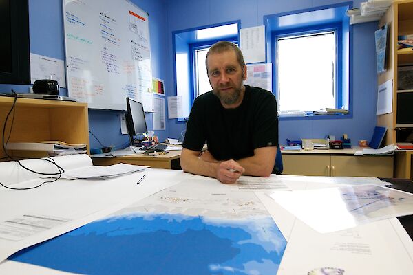 Operations specialist, Anthony Hull, in his office with a map of Antarctica