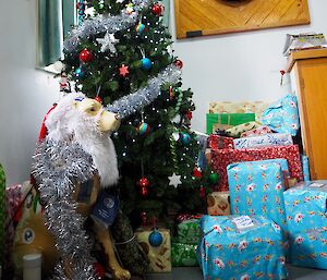 Fibreglass dog beside decorated Christmas tree.