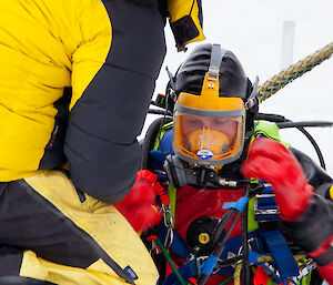 A diver makes last minute adjustments to his mask before diving through the ice