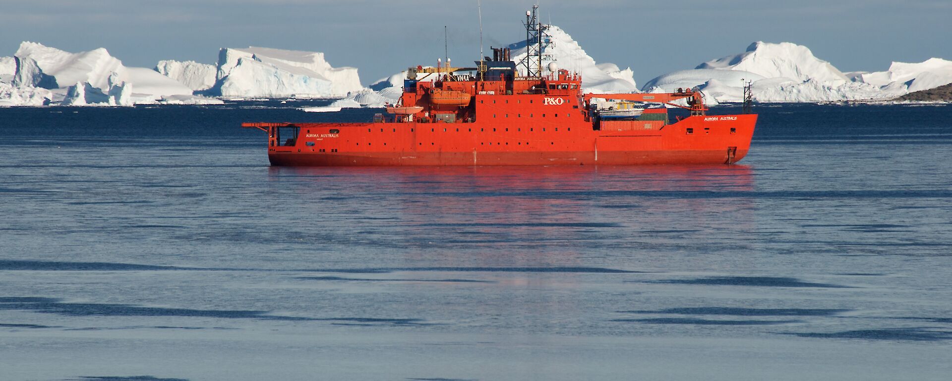 Australia’s orange icebreaker ship Aurora Australis in a sea of icebergs.