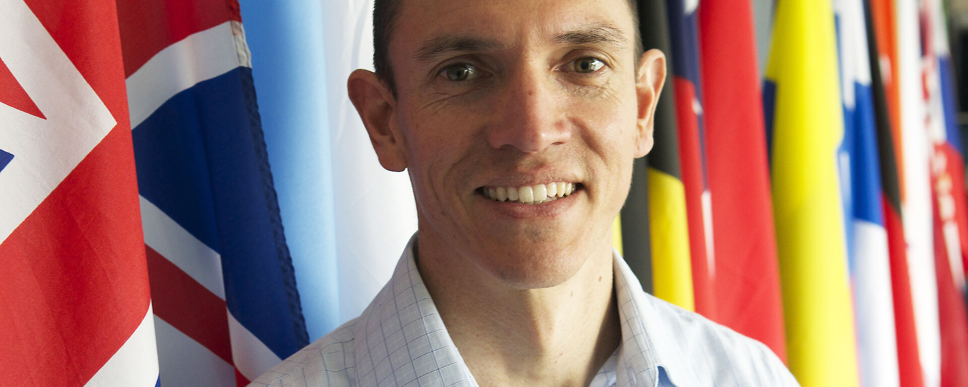 New CEP Chair, Ewan McIvor, standing in front of many nations’ flags