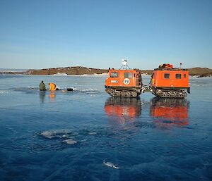 Paula and Chad, beside a Hägglunds, take water samples at Crooked Lake