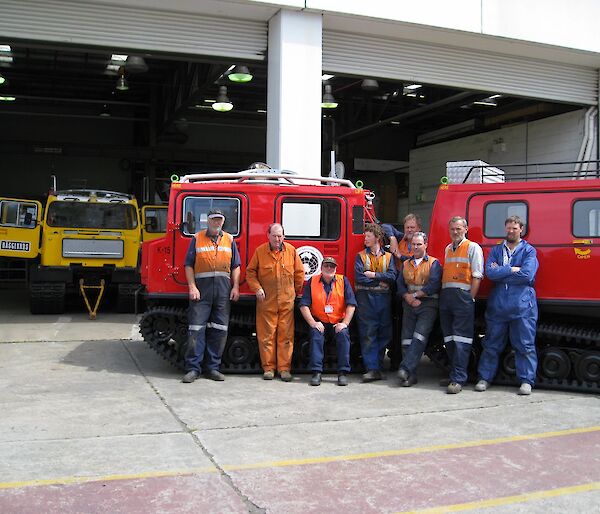 Mechanical team stands in front of refurbished red Hägglunds