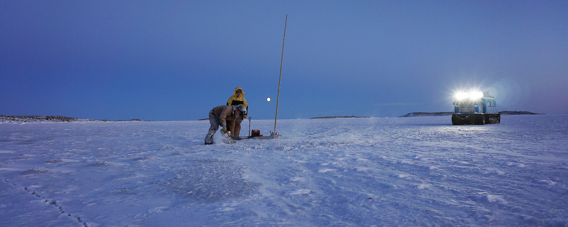 Expeditioners cutting through the ice with a chainsaw.