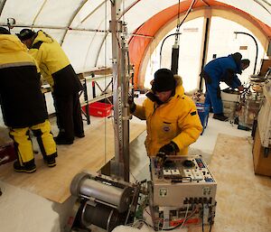 Five scientists in a drill tent with one using the Eclipse drill and others processing ice cores