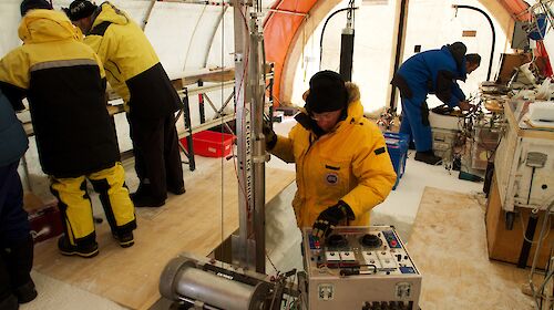 Five scientists in a drill tent with one using the Eclipse drill and others processing ice cores
