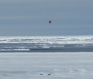 The helicopter flying across fast ice in Antarctica.