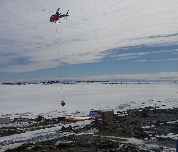 The helicopter hovers over a seawater holding tank.