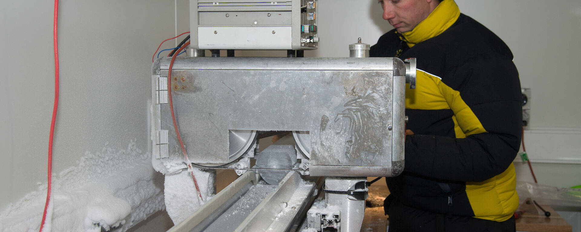 An ice core being cut with a horizontal bandsaw.