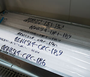 A collection of long rectangular sections or sticks of ice cores in individual plastic sleeves.
