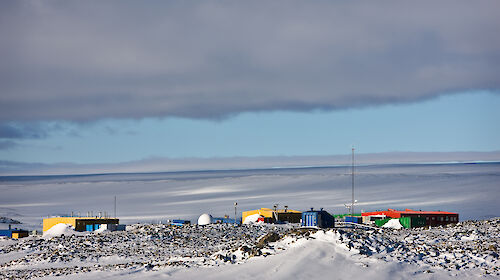 The buildings of Casey station are coloured in reds, yellows and greens and surrounded by ice.