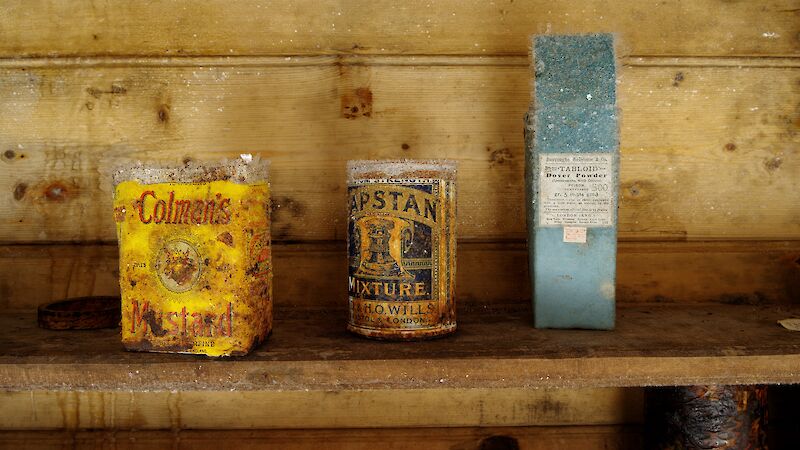 Old tin of mustard and two other original packets on an icy wooden shelf