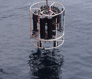 Large round piece of equipment holding sampling equipment suspended over the water
