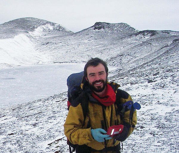 Man smiling at camera surrounded by snow on Macquarie Island.