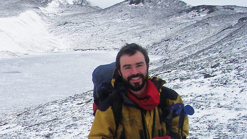 Man smiling at camera surrounded by snow on Macquarie Island.