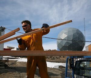 Carpenter lifting lengths of timber