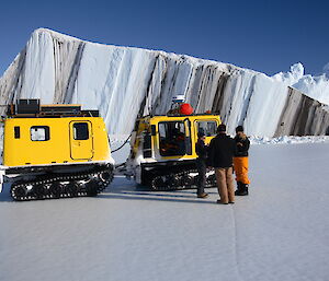 Expeditioner standing by Hägglunds parked by a huge iceberg