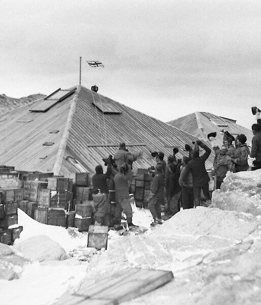 AAE expeditioners raising the flag on the completed huts at Commonwealth Bay