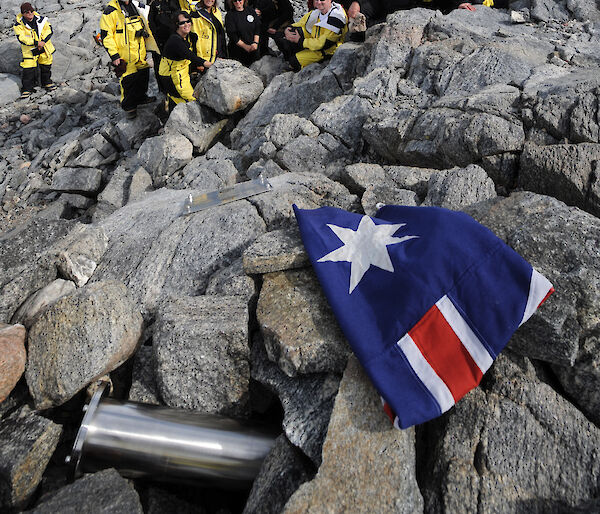 Time capsule, plaque and flag, with people in the background