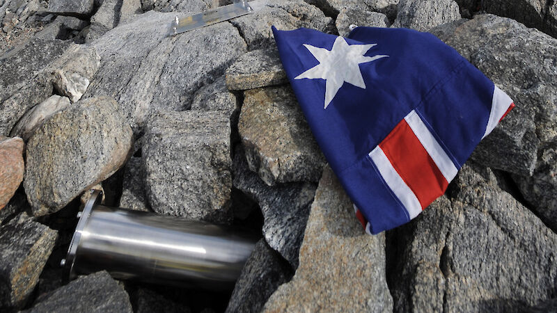 Time capsule, plaque and flag, with people in the background