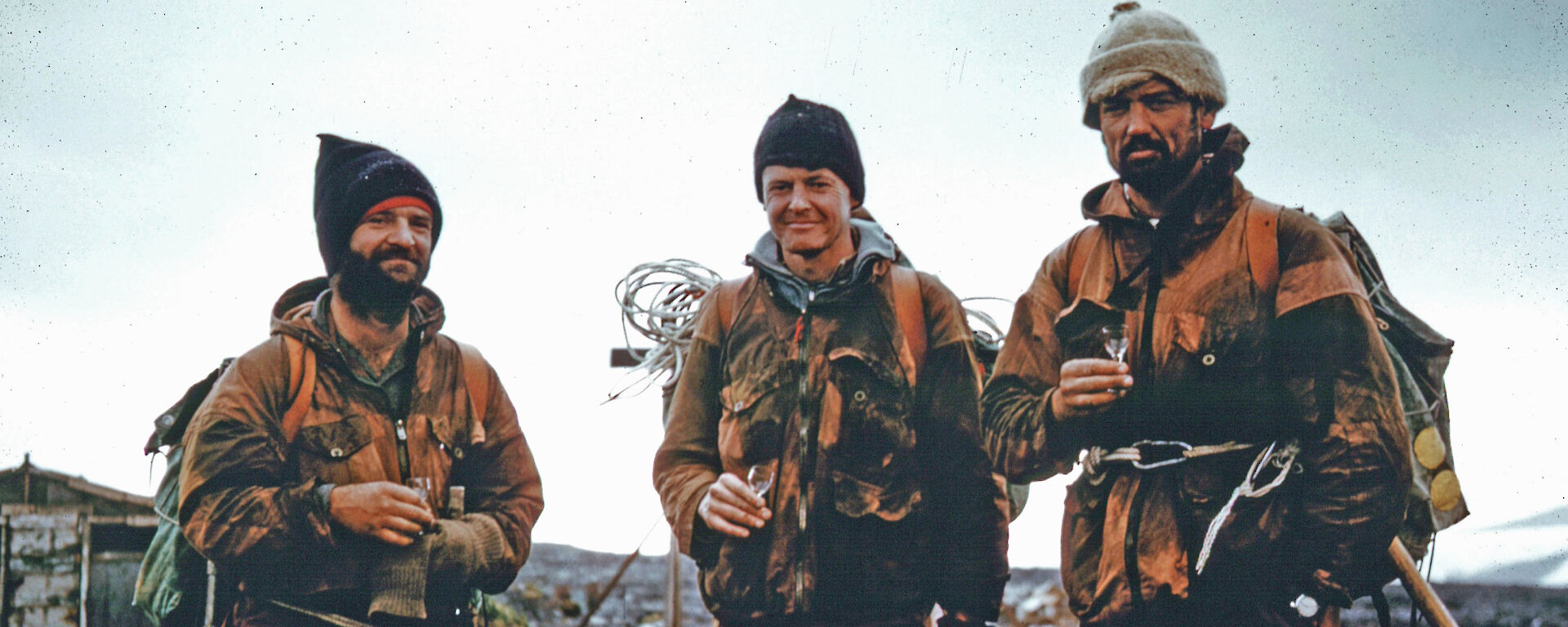 The Mountain Party share a tot of whisky on arriving at the ANARE Station, Heard Island, after their retreat from the summit plateau of Big Ben.