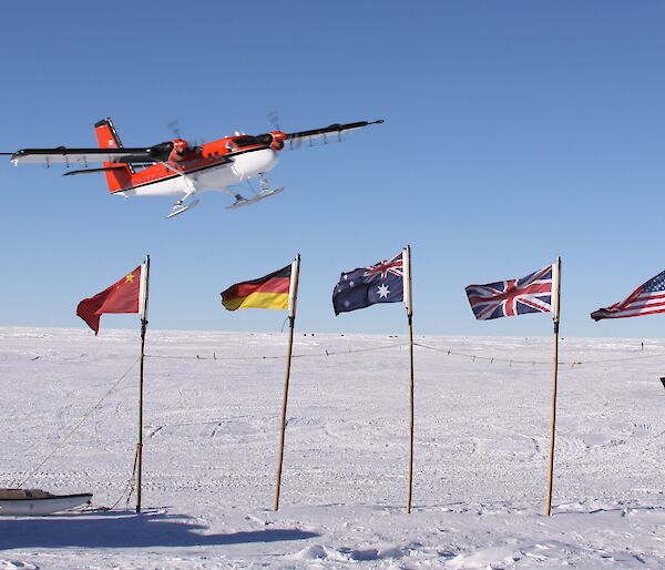 A Twin Otter flies over the flags of countries participating in AGAP.