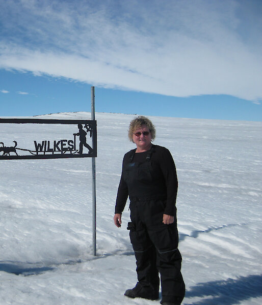 Lyn Maddock beside sign for Wilkes station