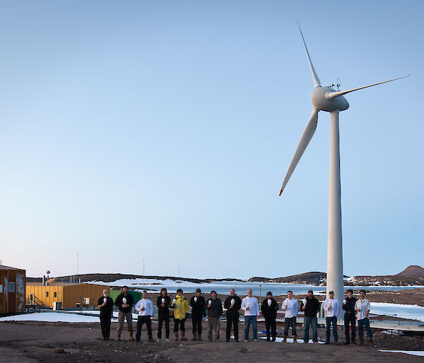Expeditioners in standing in front of the wind turbine at Mawson