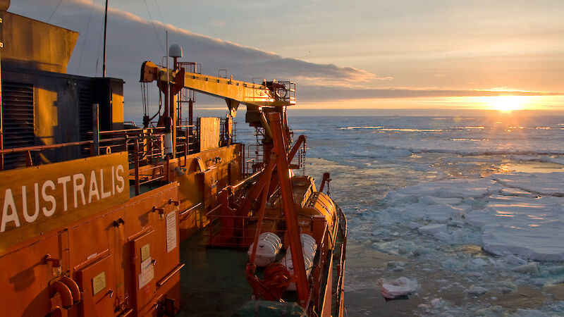 Aurora Australis in the ice, with sunset in the background