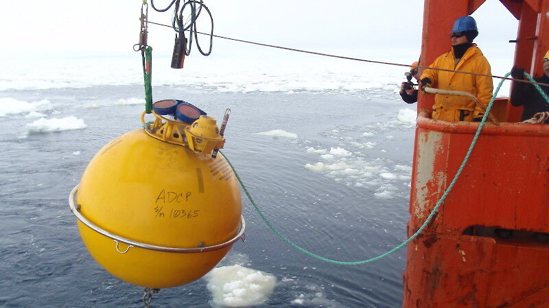 Deploying one of the large yellow buoys on a sub-surface mooring during a marine science voyage.
