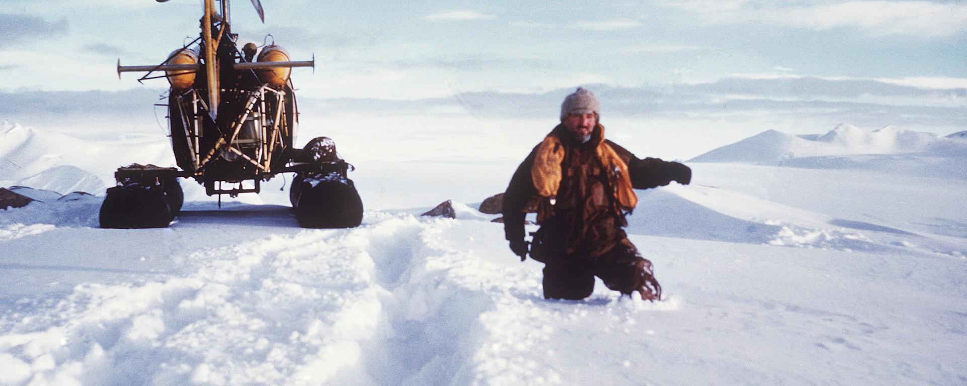 Man beside helicopter up to his waist in deep snow