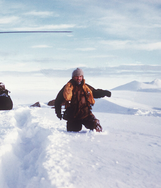 Man beside helicopter up to his waist in deep snow