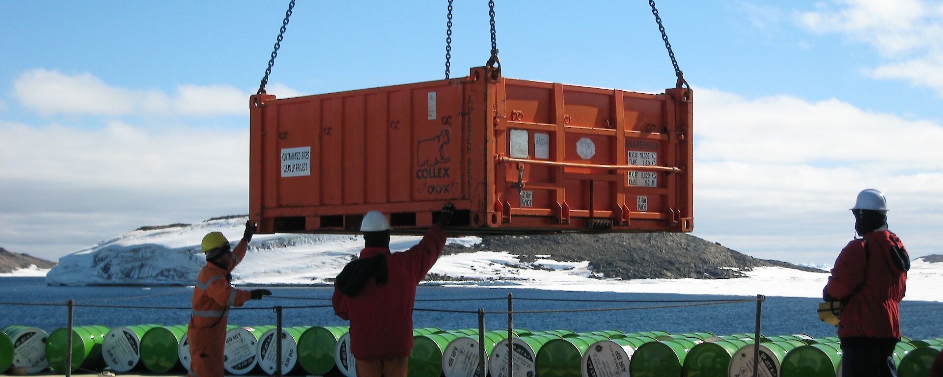 Workers on the Aurora Australis use a crane to unload cargo as part of resupply operations at Davis station