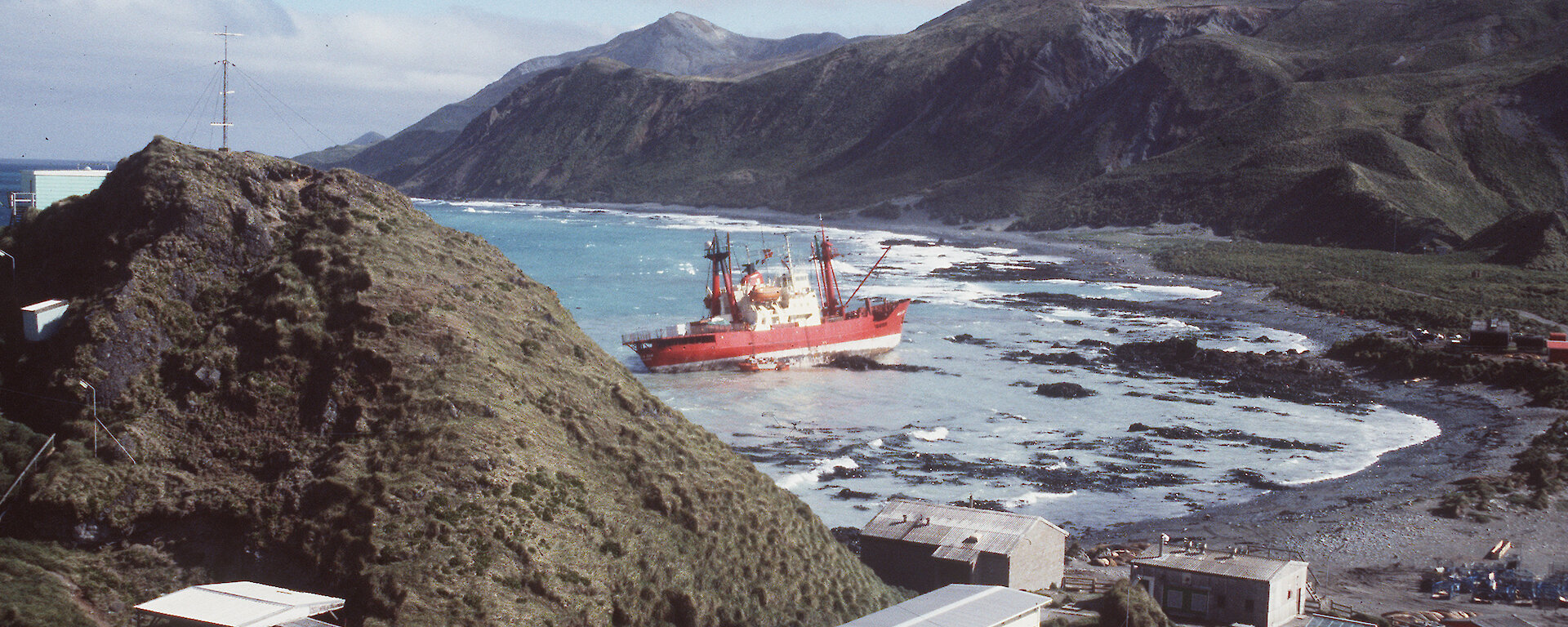 Grounded ship, the Nella Dan, up on rocks near Macquarie Island station buildings