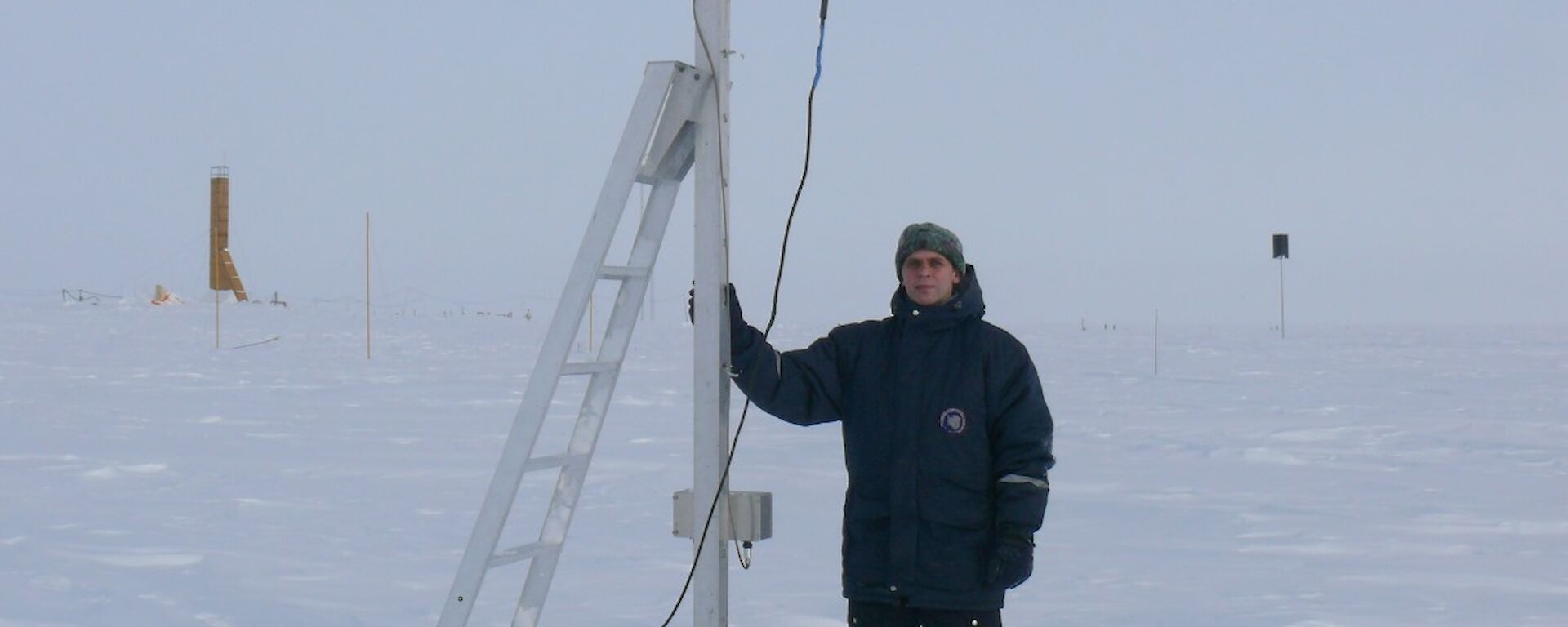 Russian scientist, Evgeny Gruzinov, standing beside an electric field mill at Vostok, Antarctica.