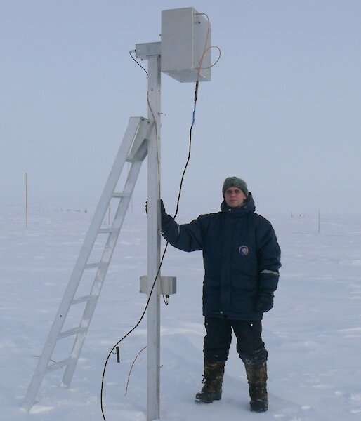 Russian scientist, Evgeny Gruzinov, standing beside an electric field mill at Vostok, Antarctica.